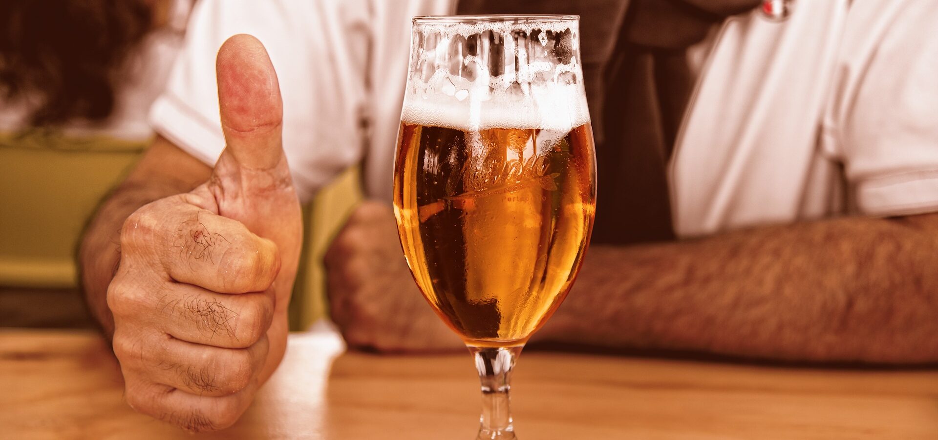 a man gives a thumbs up next to a glass of beer