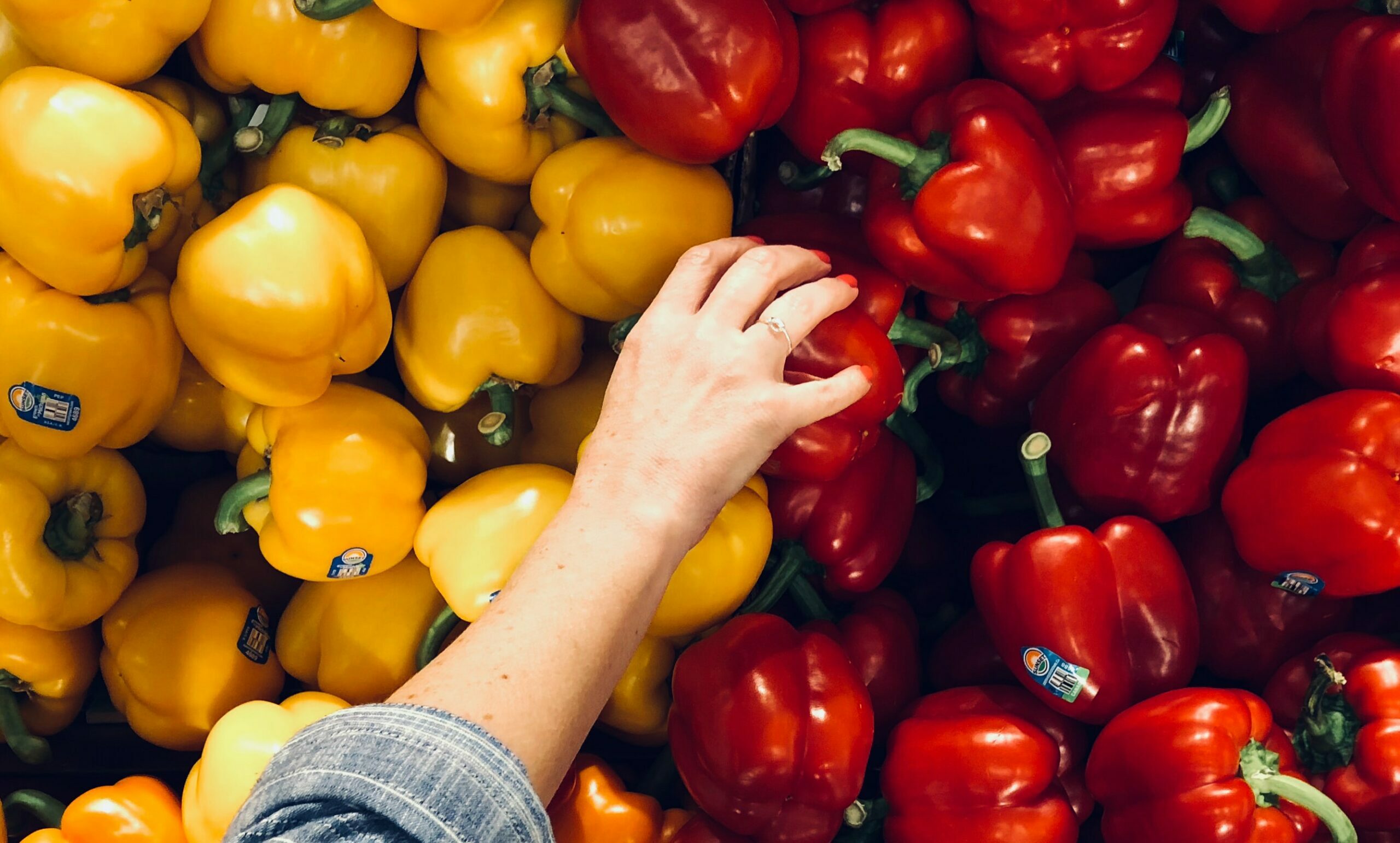 a hand reaches for a red bell pepper