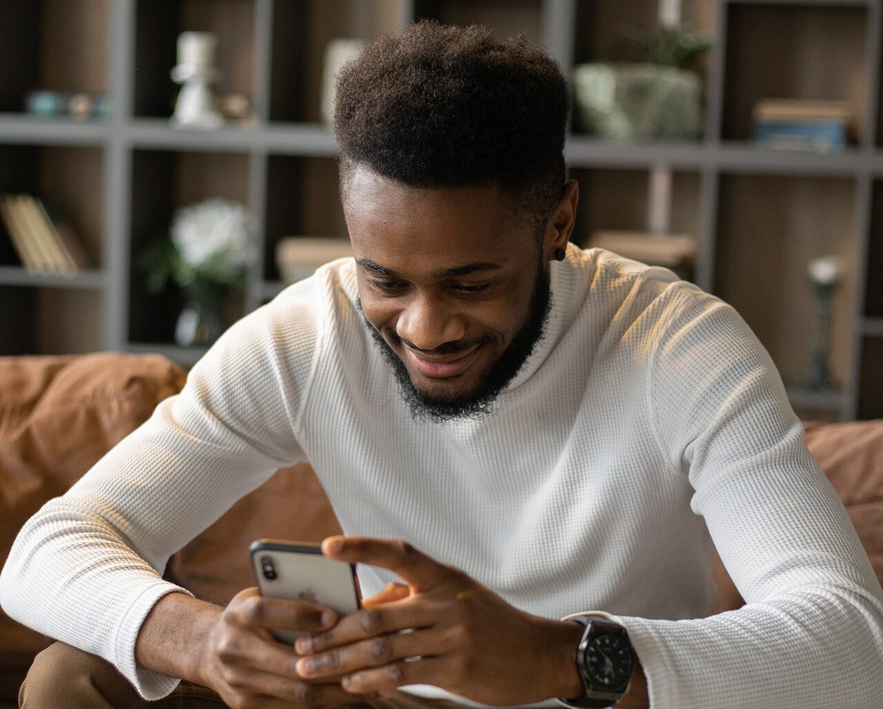 a young man smiles at his cell phone