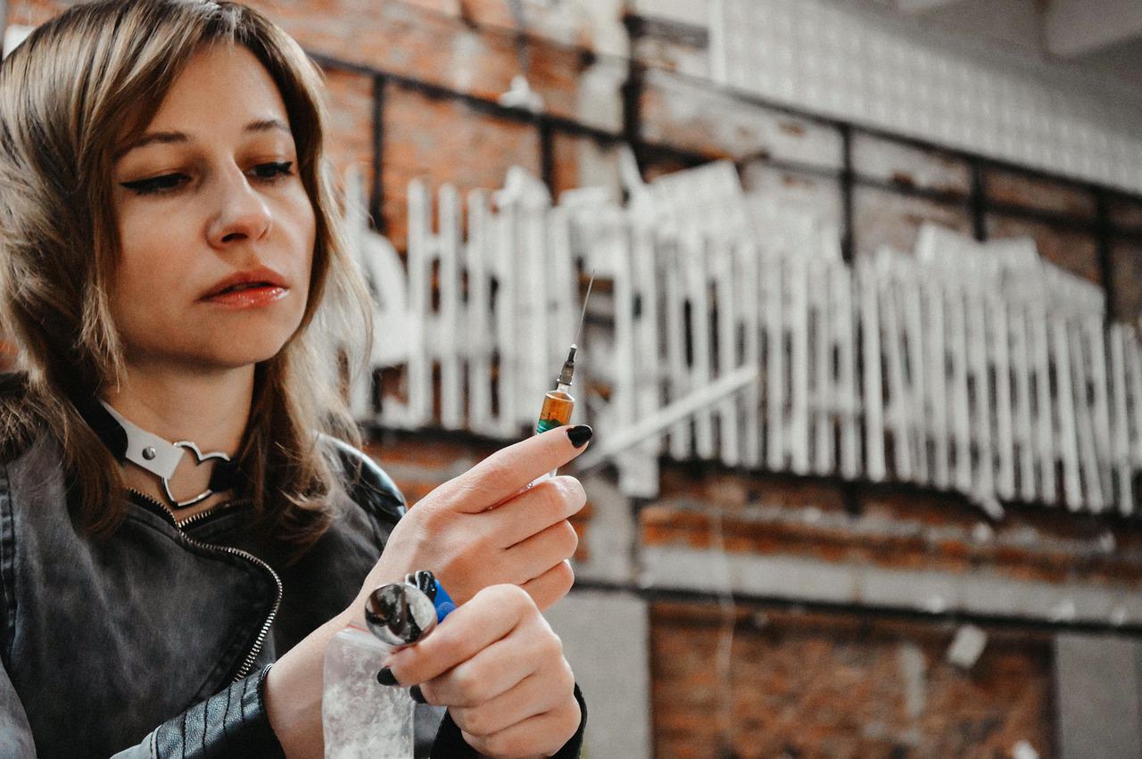 girl looks at syringe full of drugs