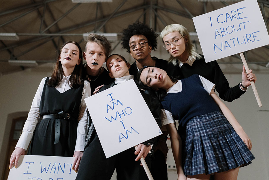 group of gen z teens hold signs saying they are who they are and that they care about nature