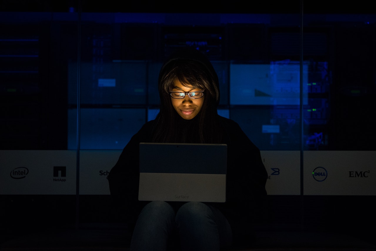 Woman sits in the dark enthralled by her companion, an AI chat bot