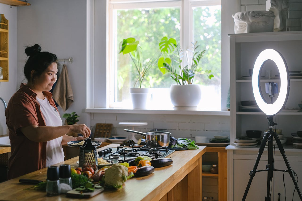 a micro influencer does a cooking show in her kitchen with a large bright ring light illuminating the space